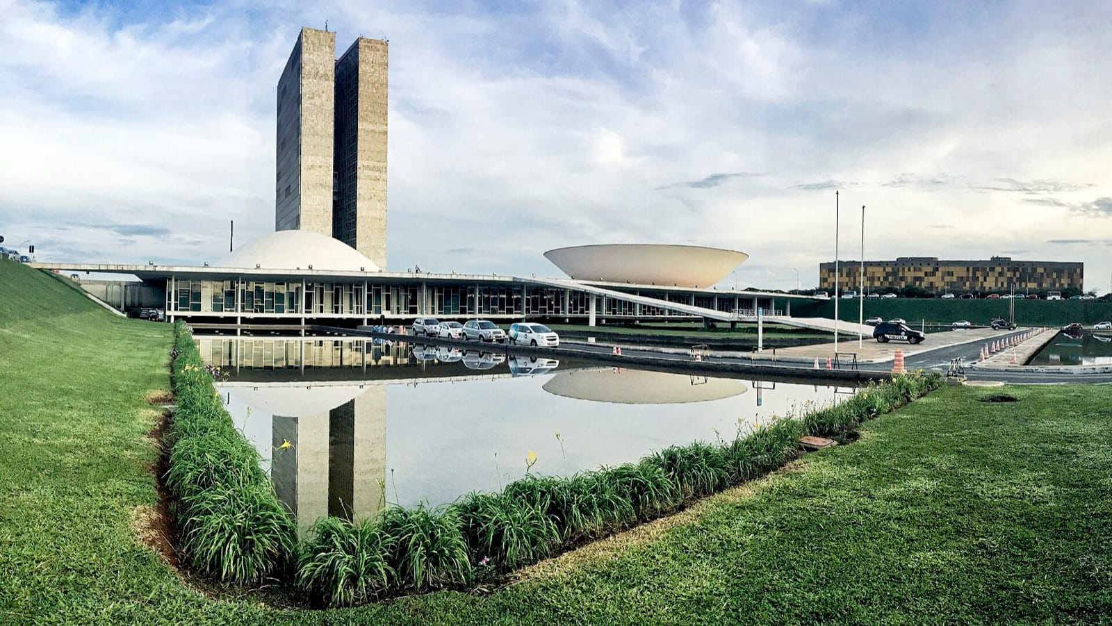 The twin towers and inverted dome of the National Congress in Brasília, reflected in the pool below