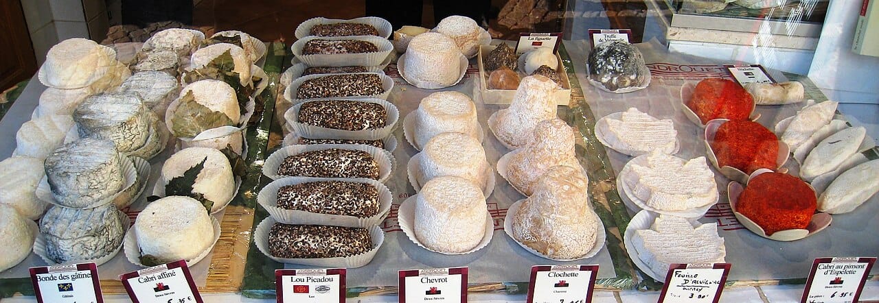 Rounds and wedges of French cheese arranged across a Paris market counter