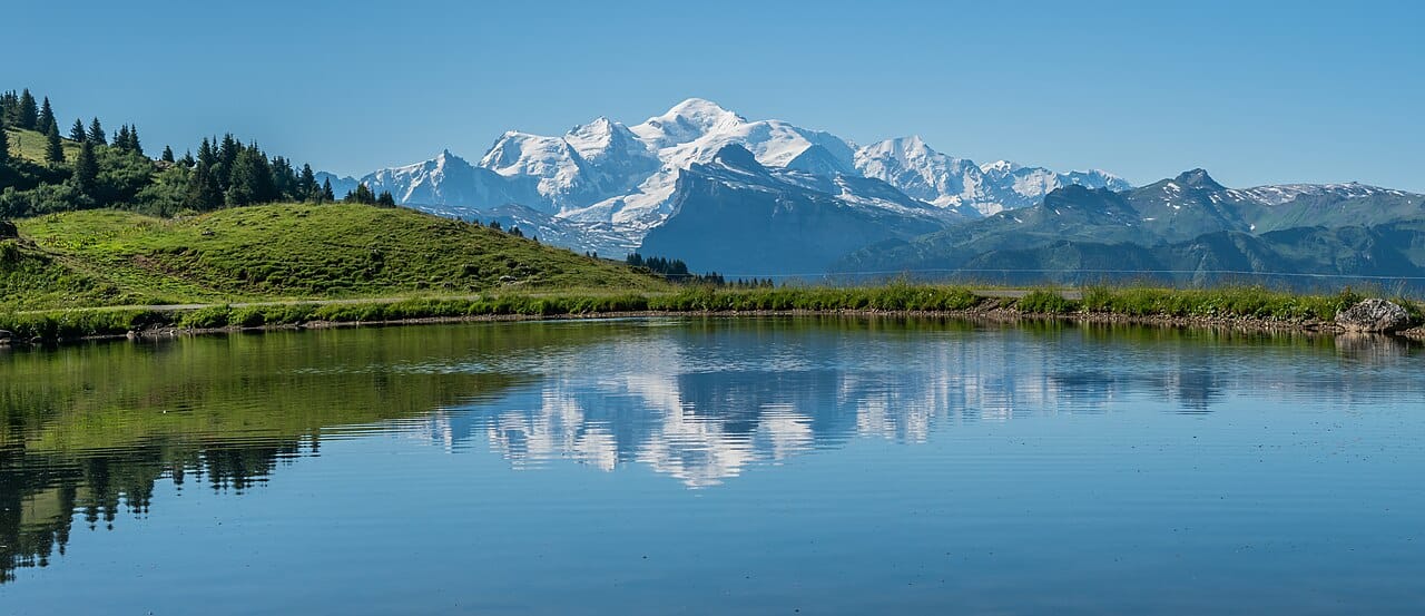 The snow-covered Mont Blanc massif seen across Lac de Joux Plane in the French Alps