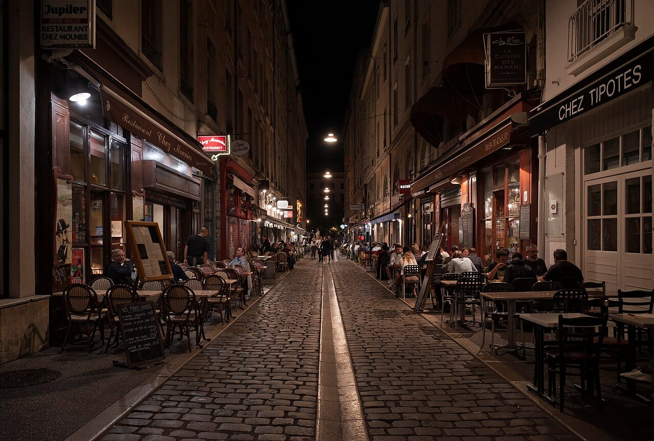 People dining at closely packed outdoor tables on Rue des Marronniers in Lyon