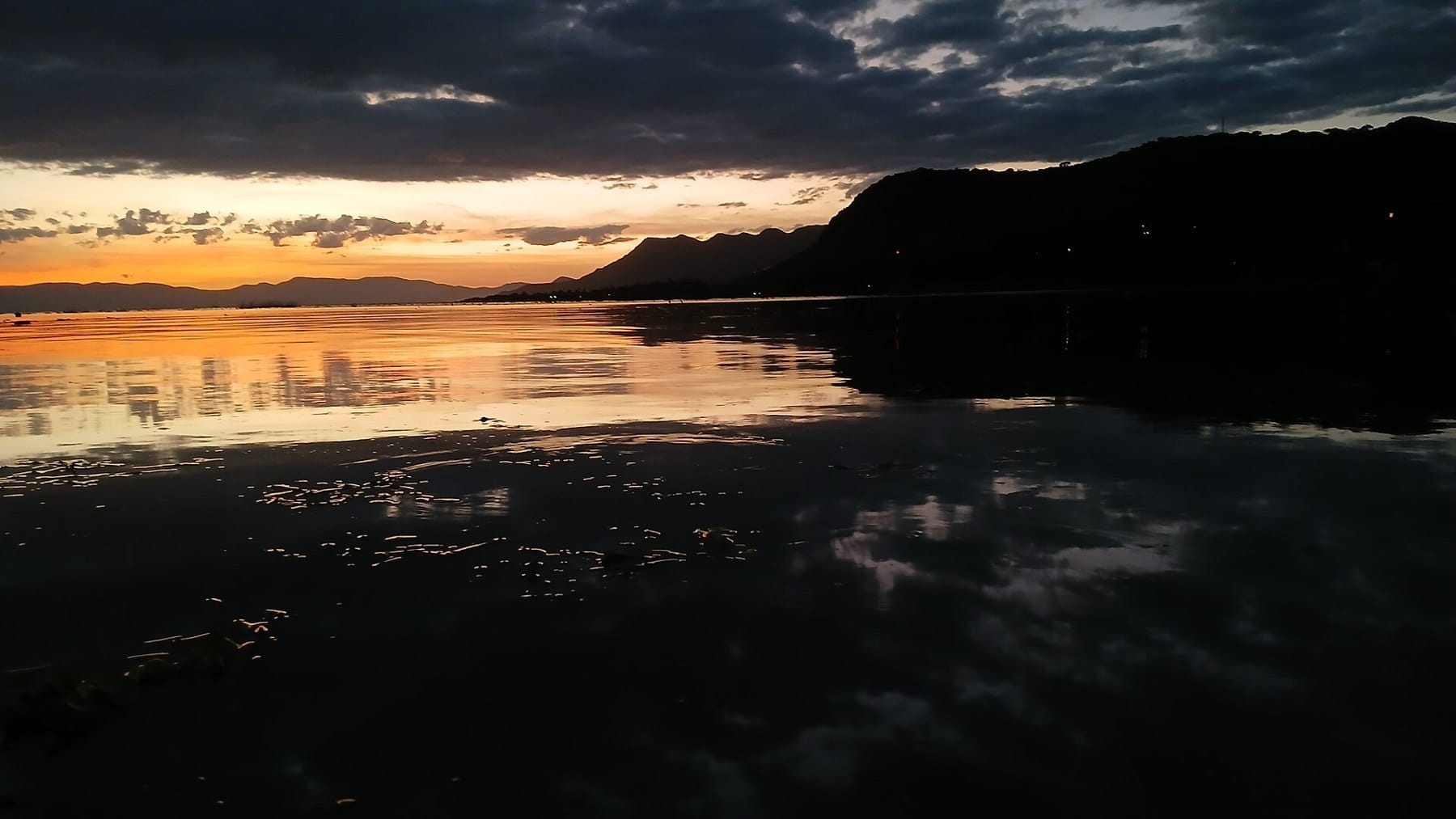 Lago de Chapala at sunset, the hills of the far shore in silhouette above still water