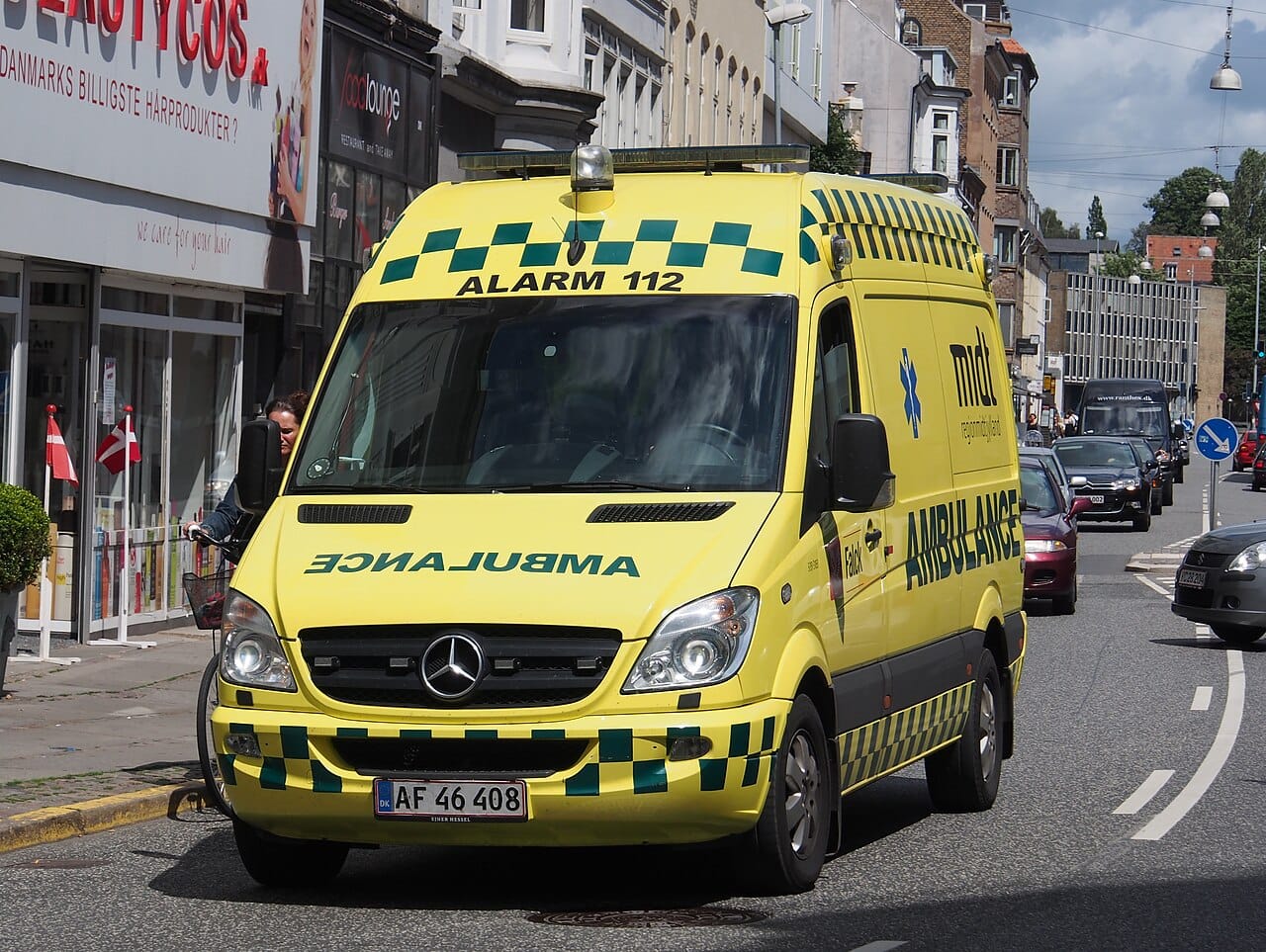 A Falck ambulance on a street in Aarhus, its roof lettered with the 112 emergency number