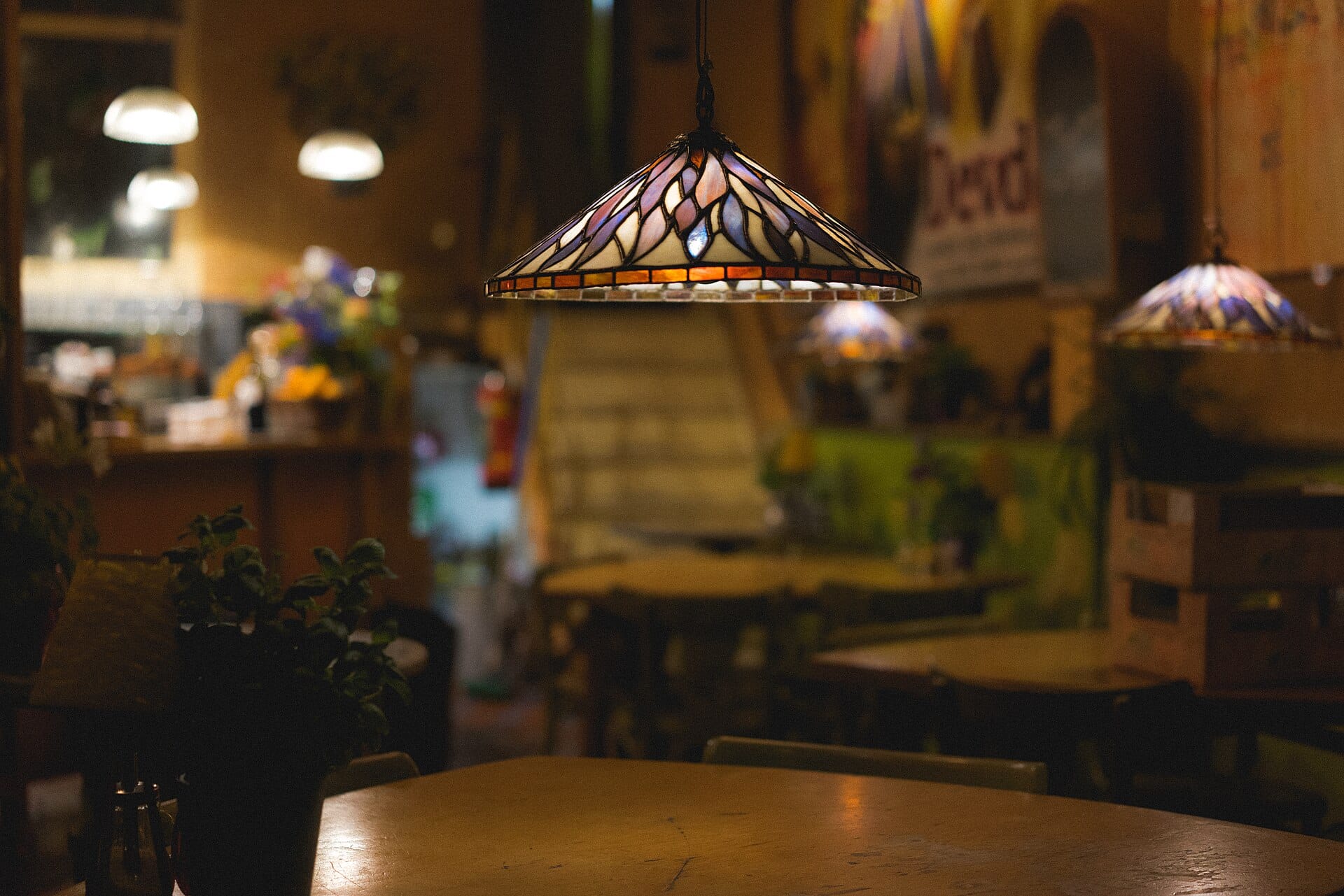 A stained glass lamp hanging over a table in a restaurant