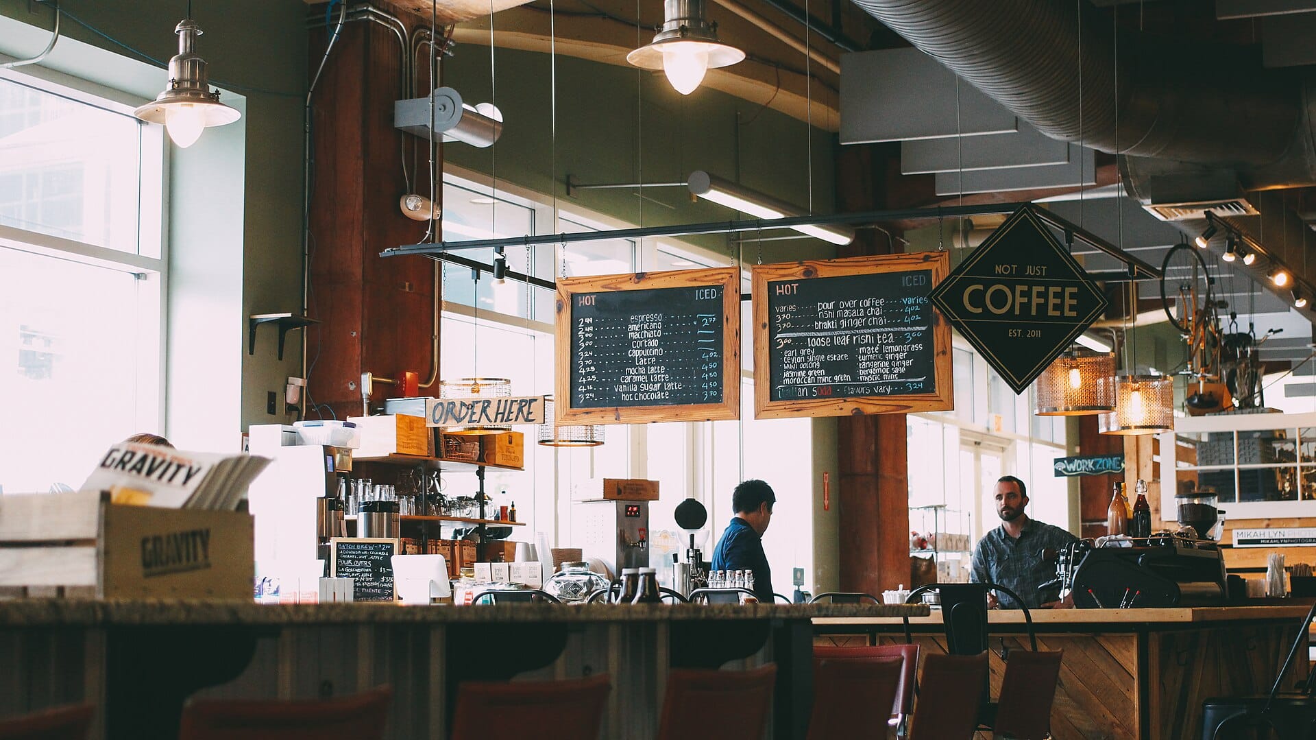 A coffee counter under chalked menu boards and an ORDER HERE sign