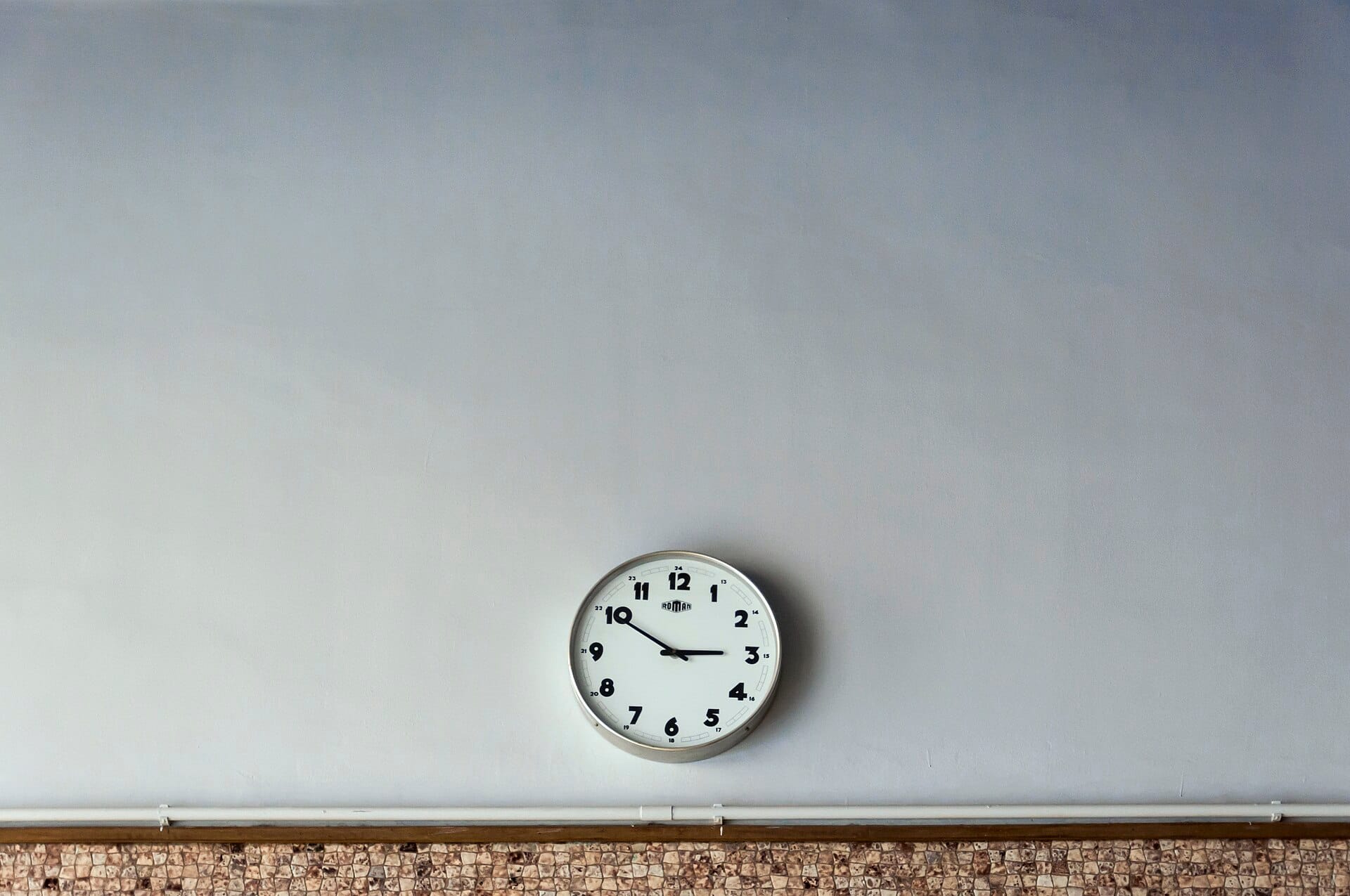 A round clock alone on a bare wall