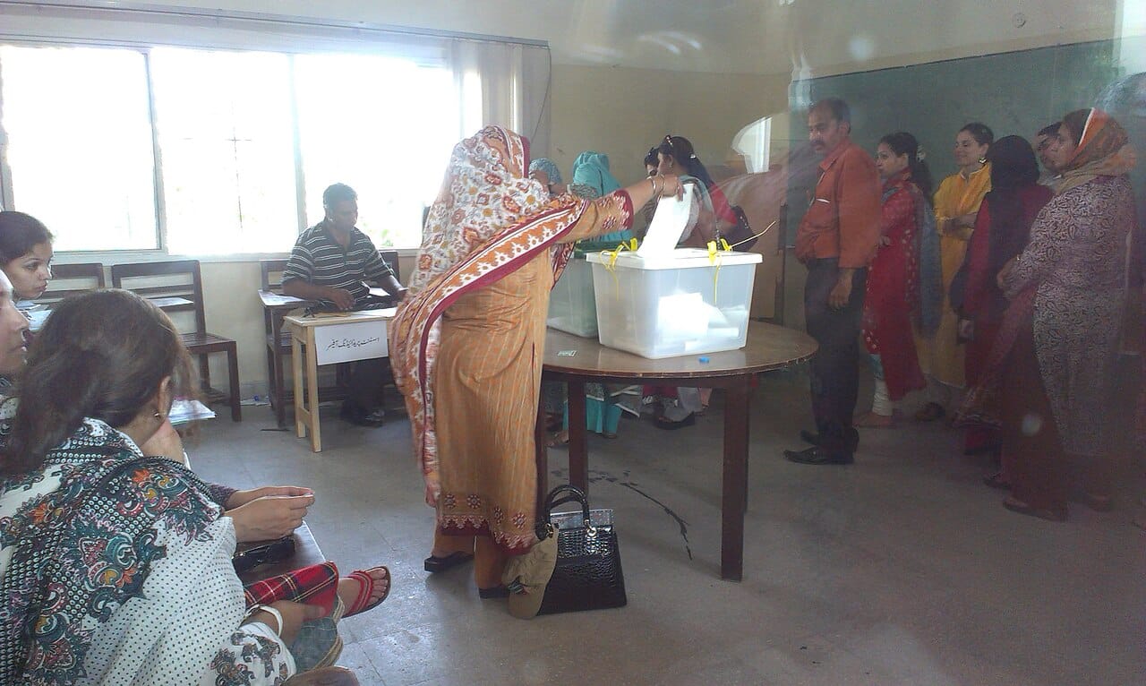 A voter folding a ballot paper into the box at a polling station