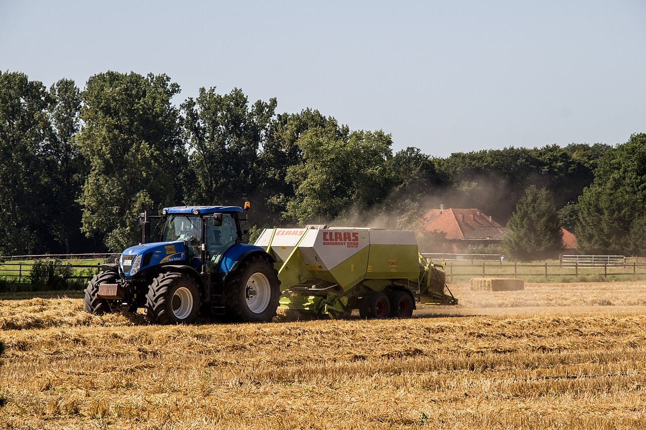 A tractor and baler working a field at harvest