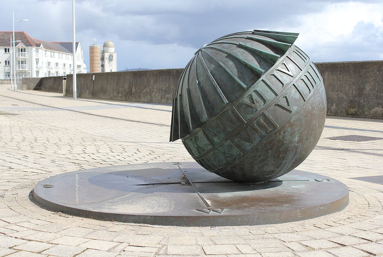 A bronze globe on a seafront, the continents raised on its face