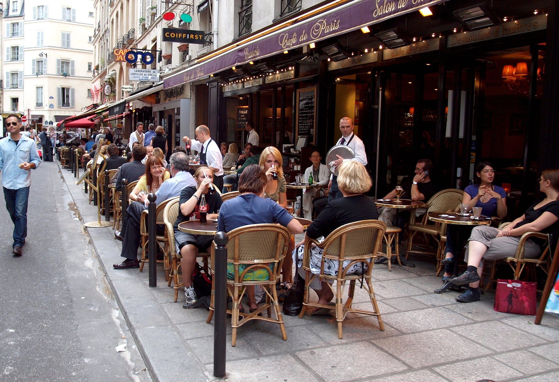 The pavement terrace of a cafe on the Rue de Buci in Paris, waiters working the tables