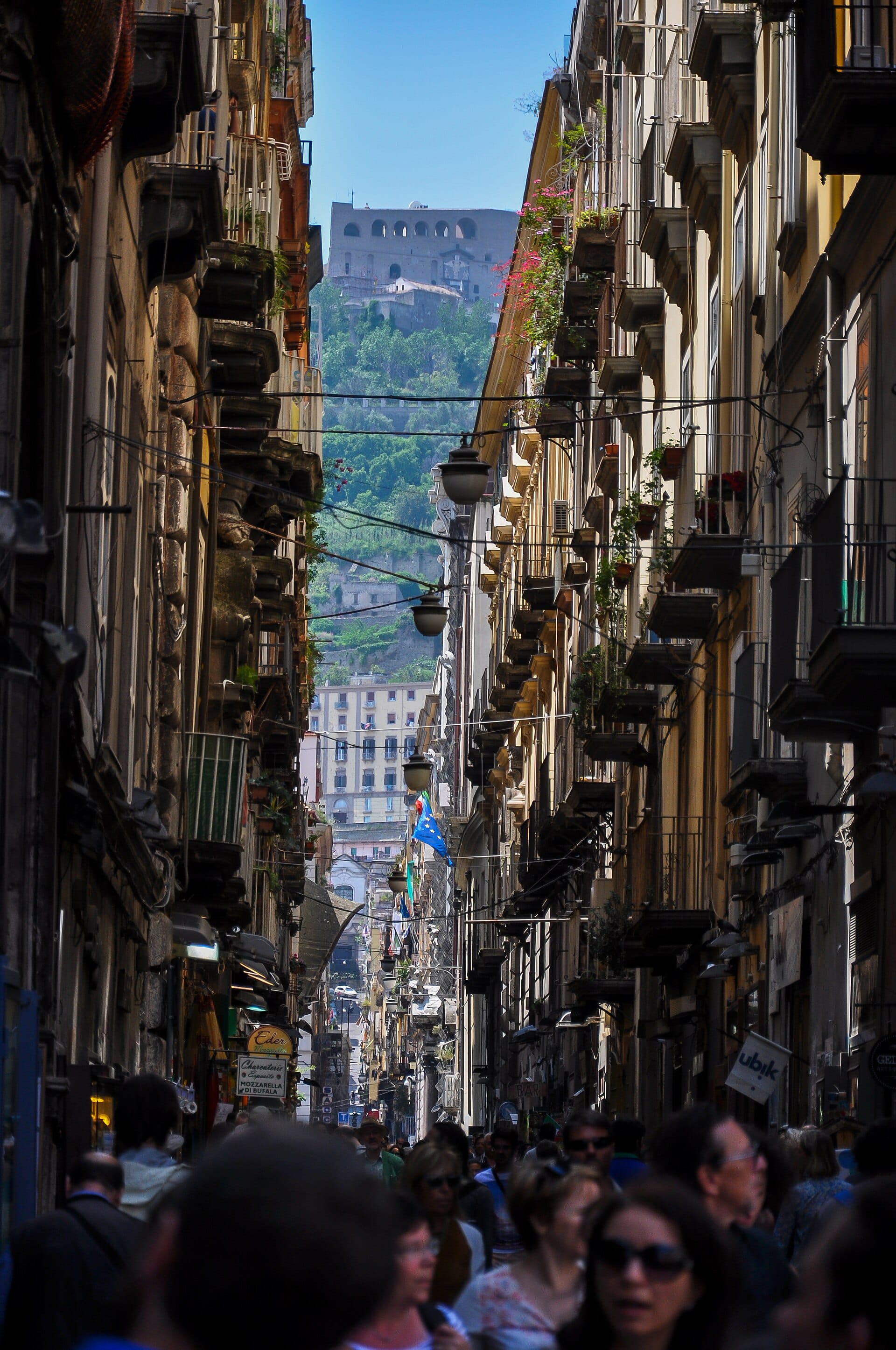 Shop signs and balconies crowding the narrow Via dei Tribunali in the old town of Naples