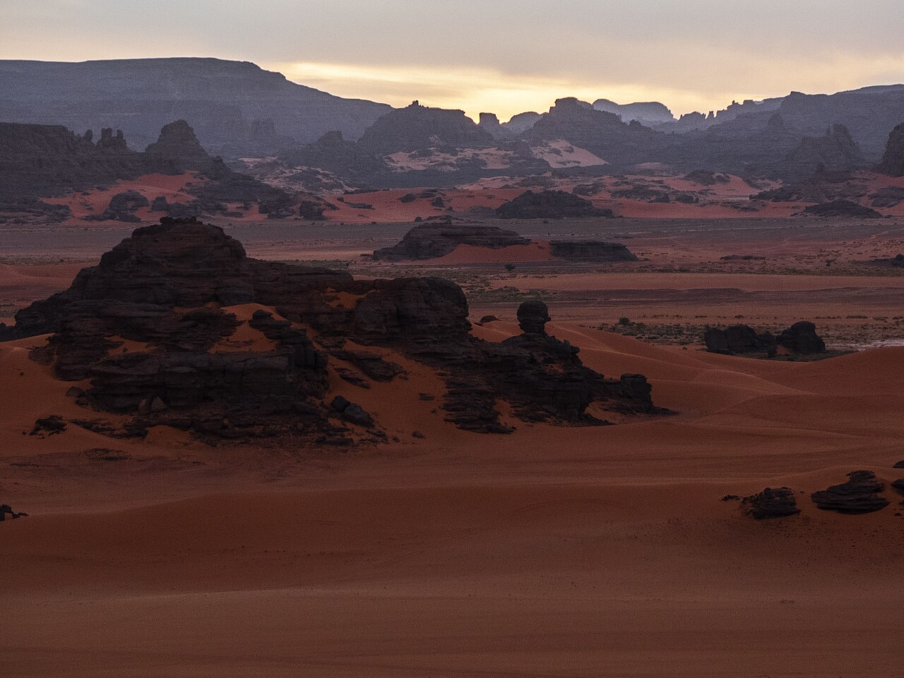 Sunset light across the orange dunes of Tin Merzouga in Algeriaโs Tadrart Rouge