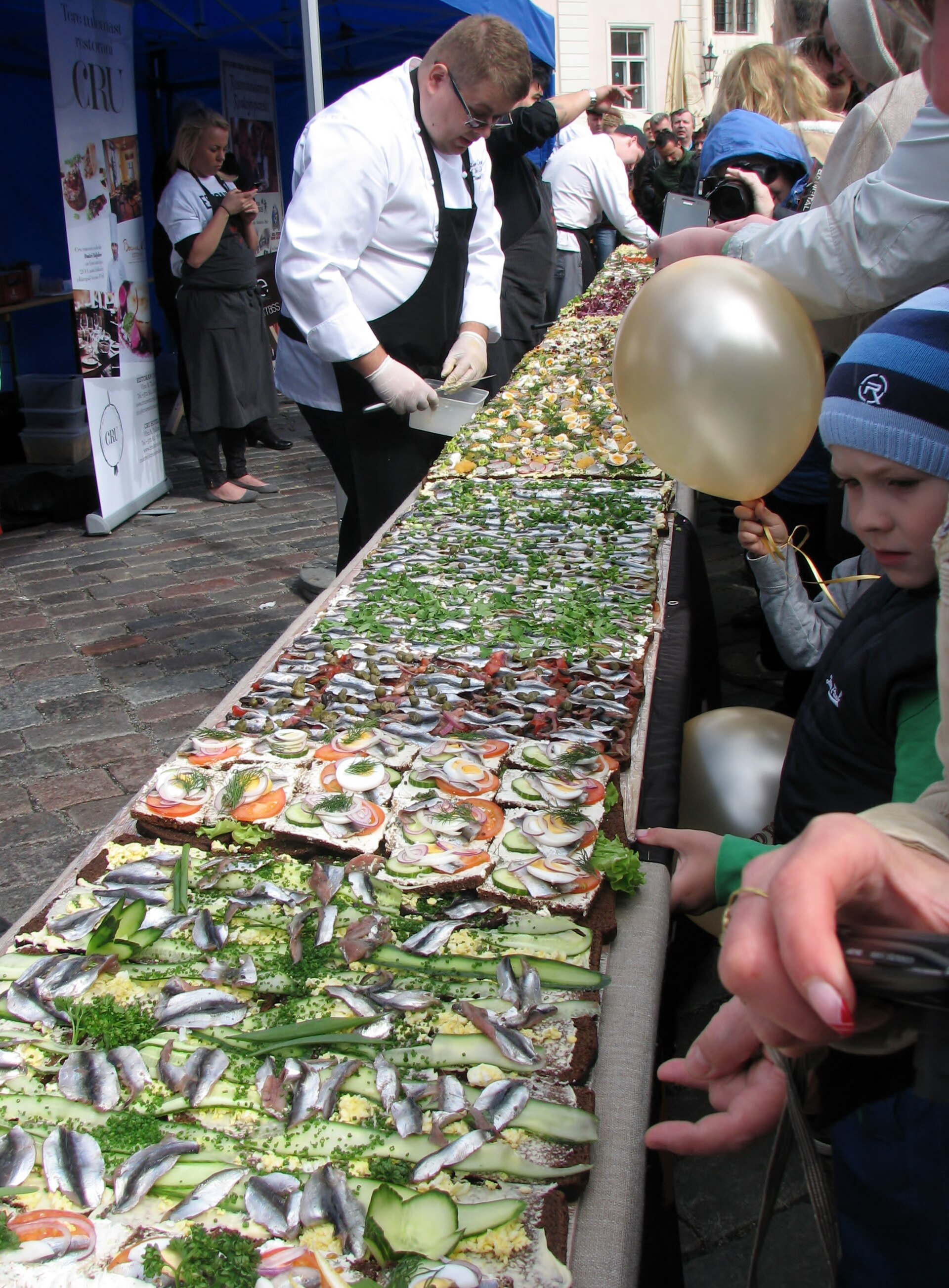 People preparing a long sprat sandwich at a food event in Estonia