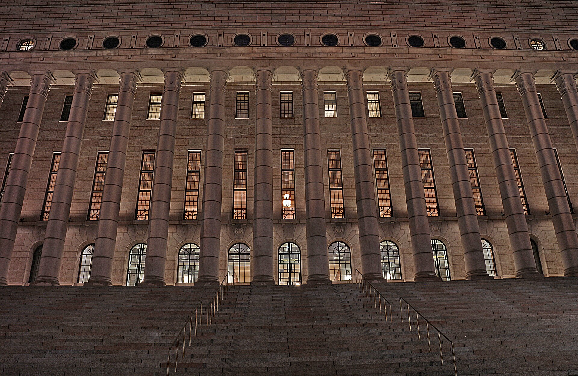 The illuminated granite facade of Finland’s Parliament House in Helsinki at dusk