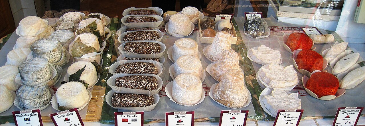 Rounds and wedges of French cheese arranged across a Paris market counter