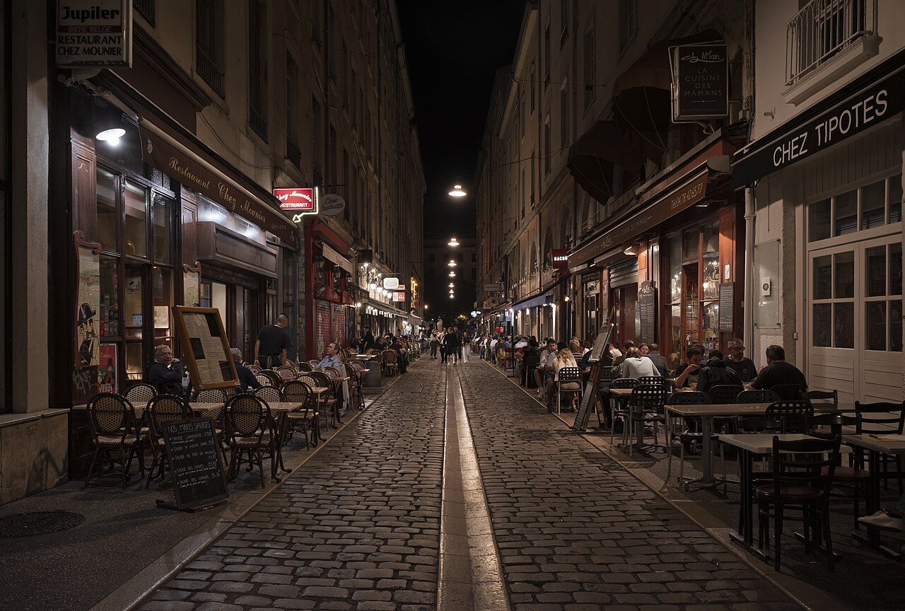 People dining at closely packed outdoor tables on Rue des Marronniers in Lyon
