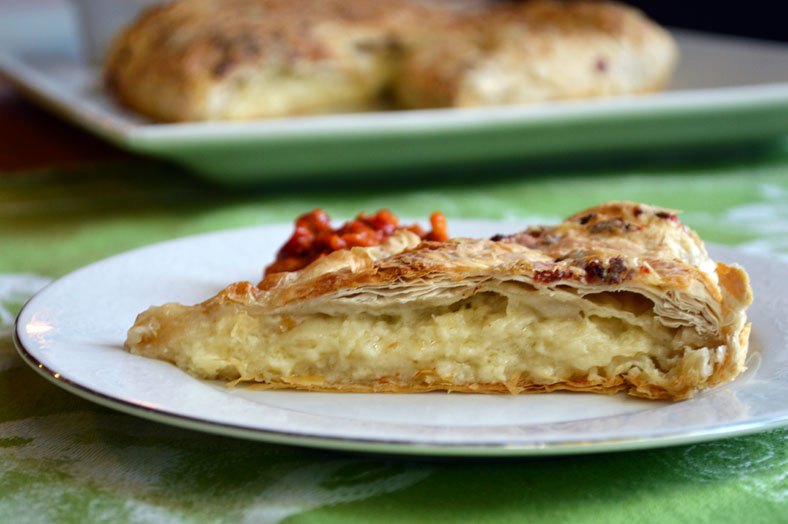 A slice of gibanica with the remaining pastry behind it
