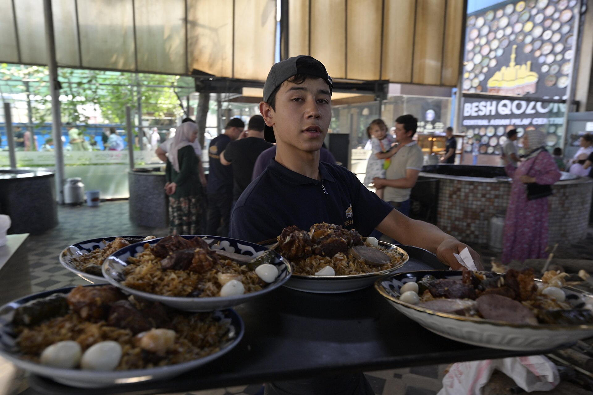A server carrying a large plate of palov