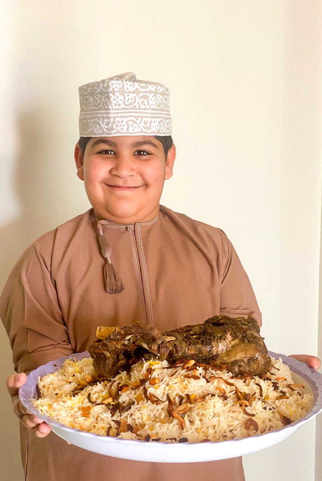 An Omani child holding a meal of shuwa