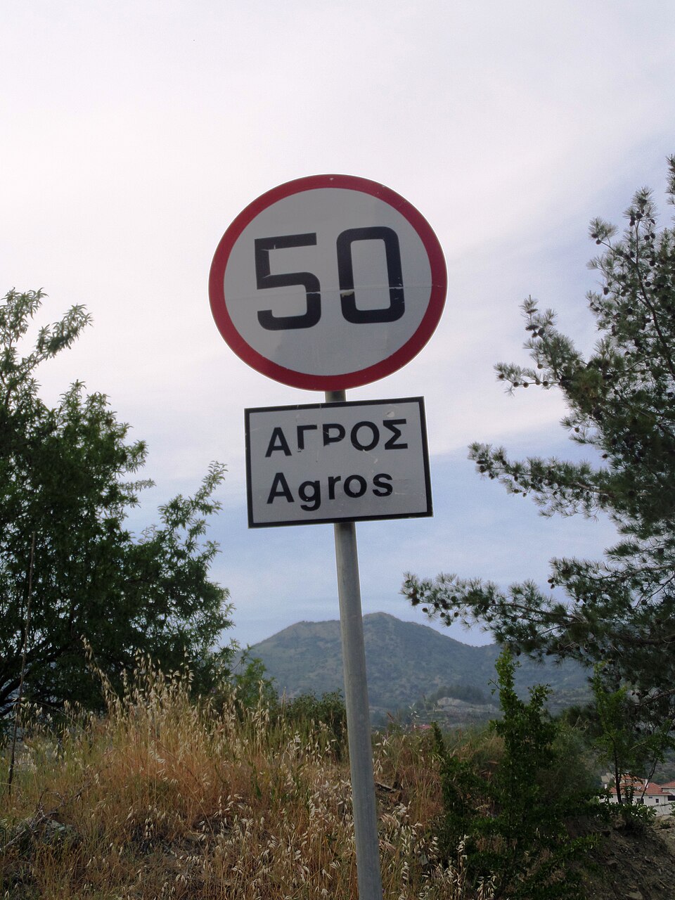 A road sign for Agros written in Greek and Latin letters in Cyprus