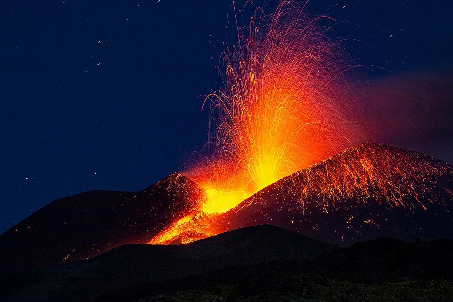 Lava fountaining from a crater on Etna at night, above the Sicilian slopes