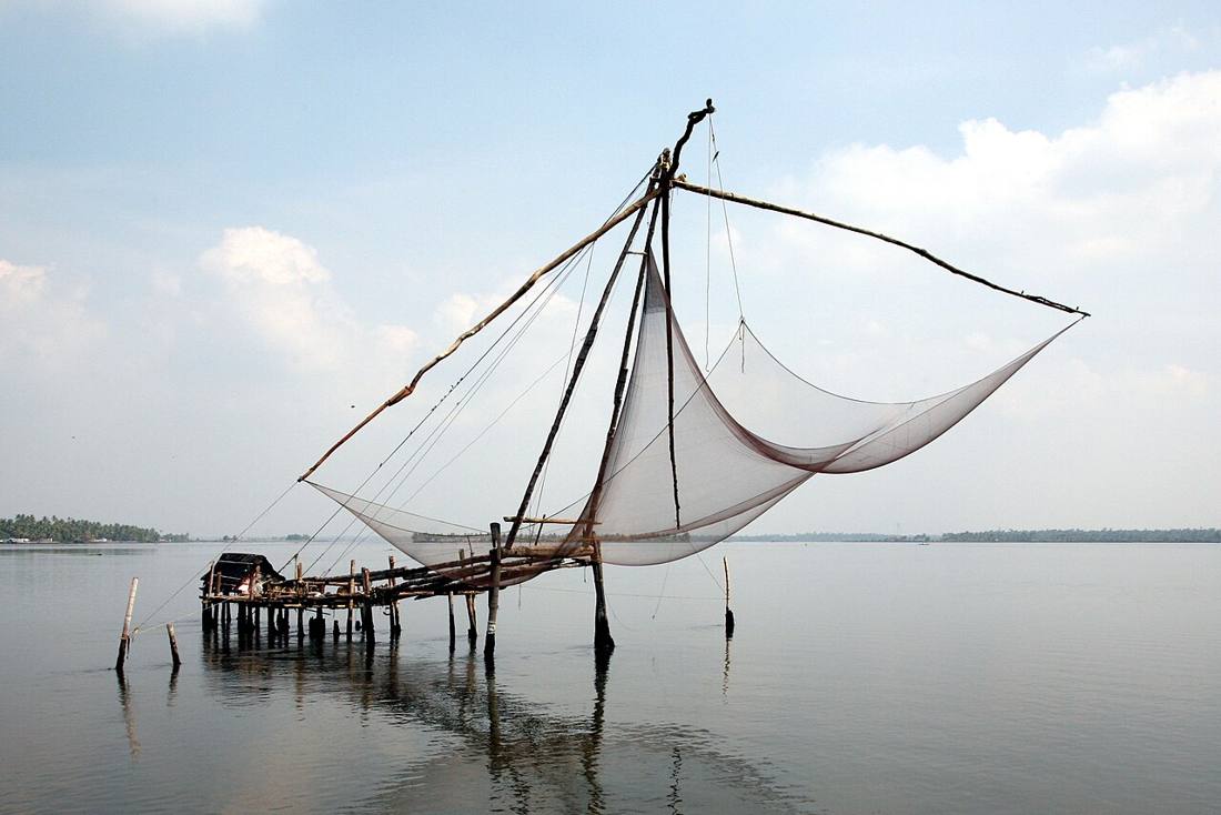 A Chinese fishing net raised on its wooden frame over calm water at Fort Kochi