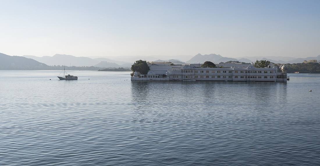 The white Lake Palace floating on Lake Pichola, hills in the haze behind
