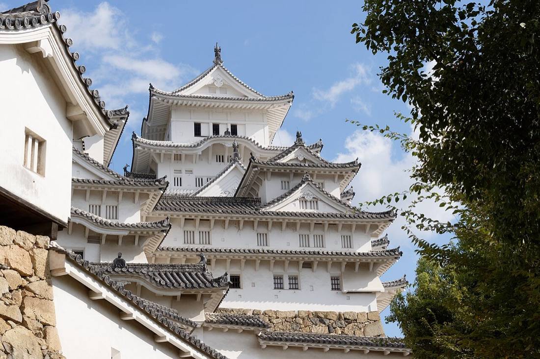 The white towers and curved roofs of Himeji Castle’s main keep against a blue sky