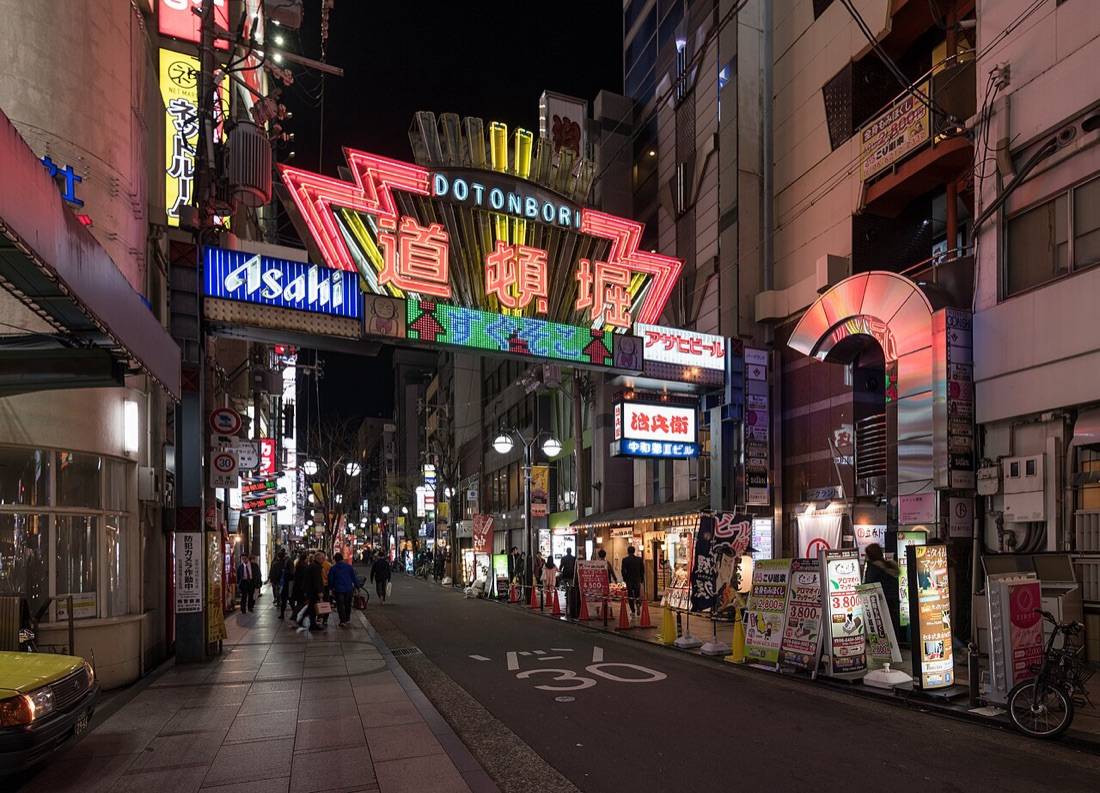The lit Dotonbori arch sign over a street of neon at night