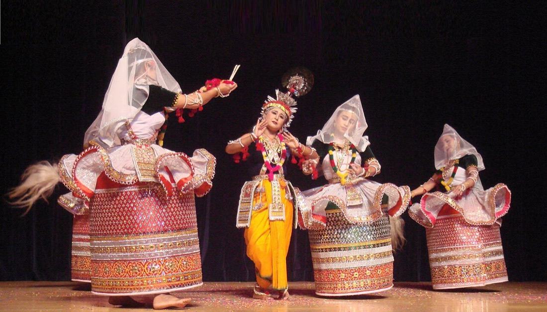 Dancers in stiff embroidered skirts performing the Ras Lila around a dancer dressed as Krishna