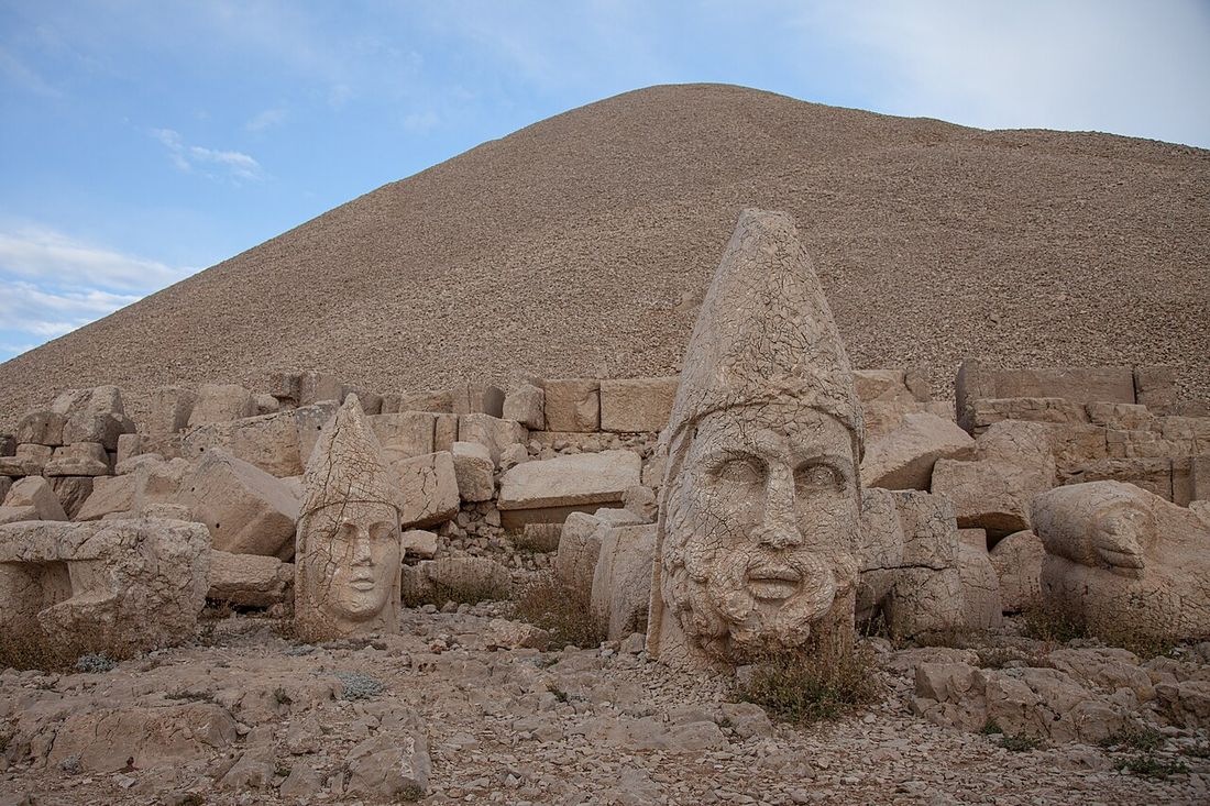 Giant carved stone heads lined up on a terrace below the pointed stone mound on the summit of Mount Nemrut