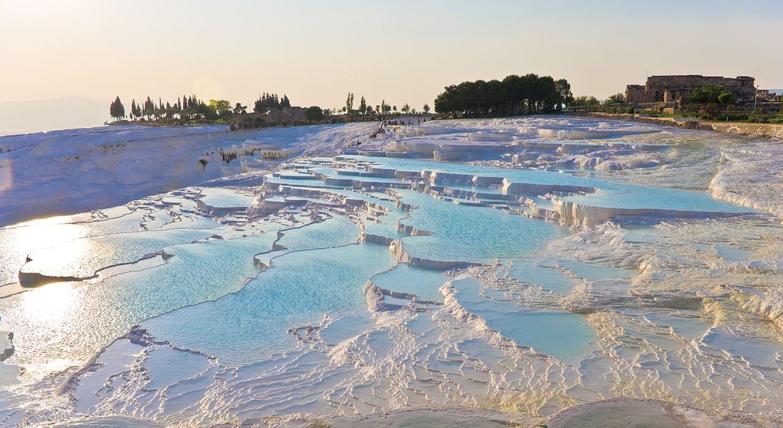 Pools of pale blue water on the white travertine terraces of Pamukkale in the evening light