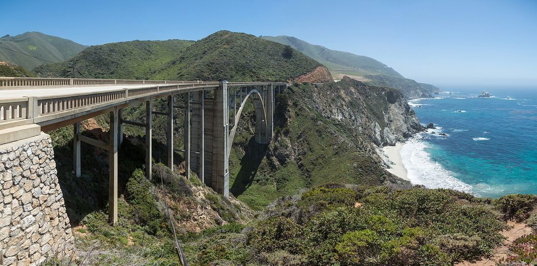 The concrete arch of Bixby Bridge spanning a canyon above the surf on the Big Sur coast