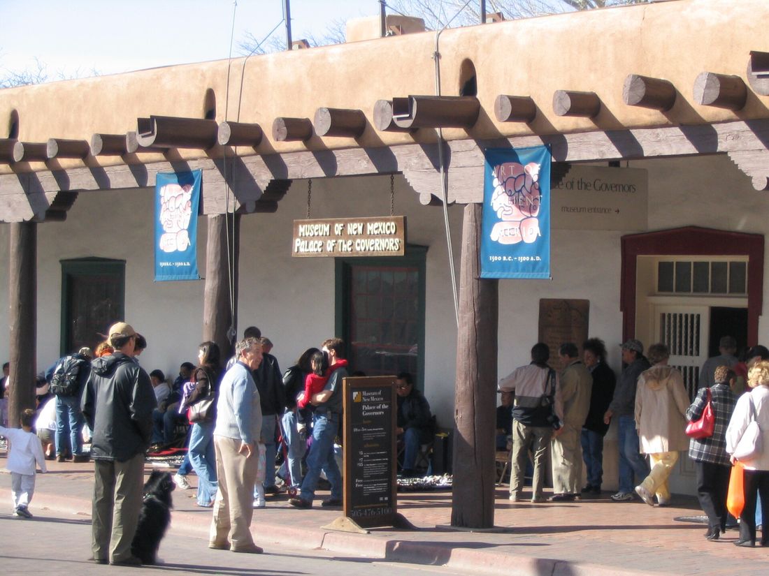 Visitors under the wooden portal of the adobe Palace of the Governors on the Santa Fe Plaza